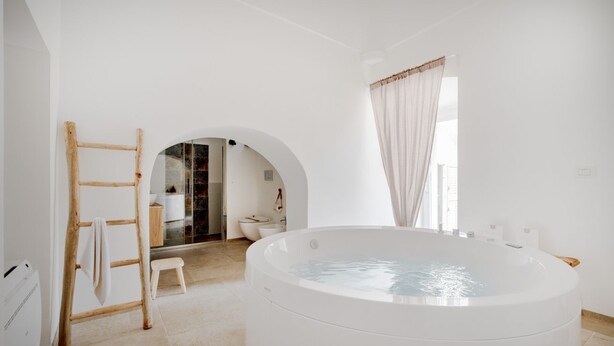 A modern bathroom with a freestanding bathtub, a wooden ladder, and a small stool. - GuestHost Borgo Lucia with pool - Trullo Catenella (Selva di Fasano)