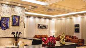 A modern lobby with a reception desk, seating area, and decorative wall panels. - 4 Guys Hotels (Muscat)