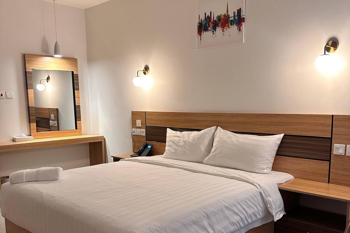 A modern hotel room with a large bed, bedside tables, a desk, and a chair.