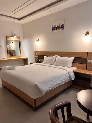 A modern hotel room with a large bed, bedside tables, a desk, and a chair. - 4 Guys Hotels (Muscat)