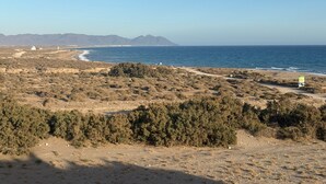 A coastal landscape with a beach, sparse vegetation, and distant mountains. - Playamar Retamar, is in first line of beach, urbanization with swimming pool.  (Retamar)