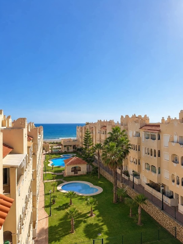 A resort with multiple swimming pools, a beach view, and a courtyard with palm trees.