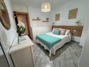 A bedroom with a bed, a dresser, a mirror, and a hanging light fixture.