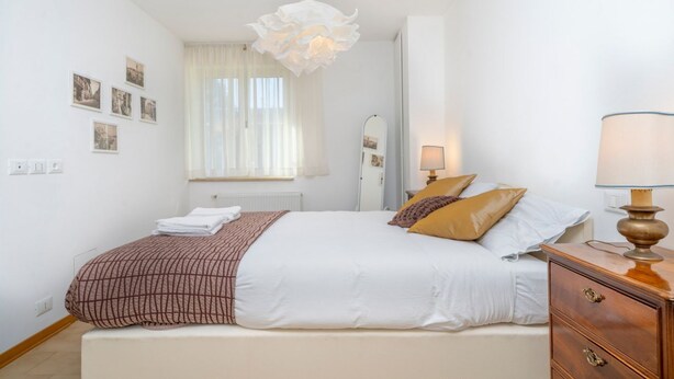 A bedroom with a bed, bedside lamps, a dresser, a mirror, and a chandelier. - GuestHost - Relax & Spacious Apartment X6 (Udine)