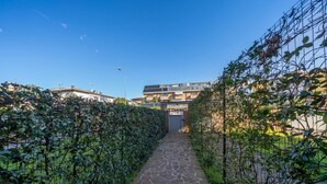 A stone pathway leading to a building entrance, flanked by dense green hedges. - GuestHost - Relax & Spacious Apartment X6 (Udine)