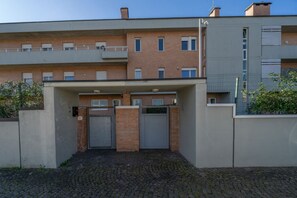 A multi-story residential building with a central entrance, brick facade, and a gated driveway. - GuestHost - Relaxing & Spacious Apartment for 6 (Udine)