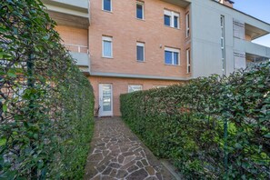 A narrow stone pathway leading to a brick building with multiple windows and a door. - GuestHost - Relaxing & Spacious Apartment for 6 (Udine)