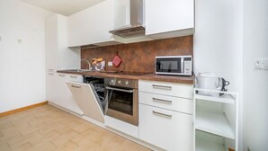 A modern kitchen with white cabinets, a stainless steel oven, a microwave, and a dish rack. - GuestHost - Relax & Spacious Apartment X6 (Udine)