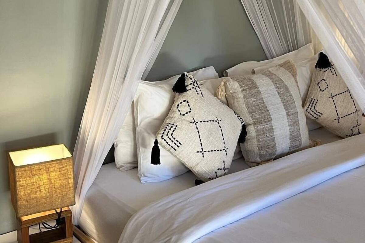 Un lit à baldaquin, une lampe de chevet et des coussins à motifs.