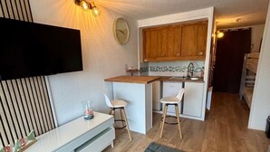 A compact living space with a kitchenette, a dining area, and a seating area with a modern chair. - Newly renovated apartment 10 minutes from Collioure market. Ideal for families. (Collioure)