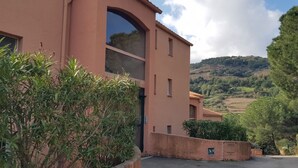 A building with a large arched window and a view of a hilly landscape. - Newly renovated apartment 10 minutes from Collioure market. Ideal for families. (Collioure)