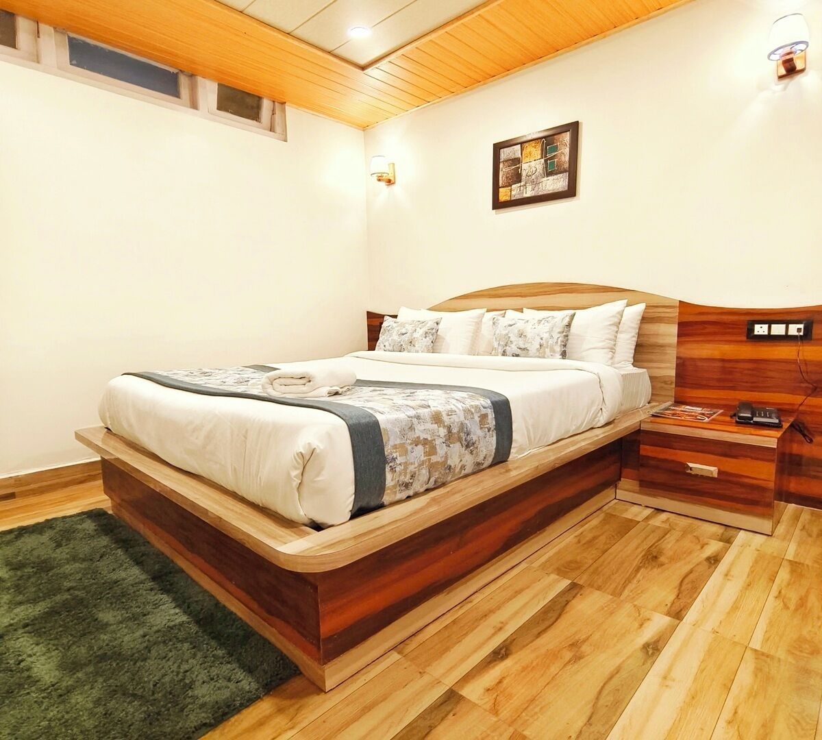 Ein Schlafzimmer mit einem Bettgestell aus Holz, einem Nachttisch, einer Lampe und einem Bild an der Wand.