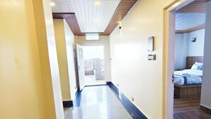 Ein Hotelkorridor mit einem polierten Boden, einer Tür zu einem Zimmer mit einem Bett und Blick auf den Balkon.