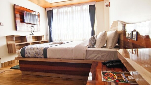 Ein modernes Schlafzimmer mit einem Bett, einem Nachttisch und einem an der Wand befestigten Fernseher.