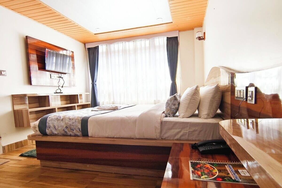 Una camera da letto moderna con un letto, un comodino e una TV a parete.
