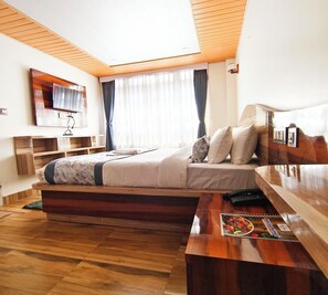 A modern bedroom with a bed, bedside table, and a TV mounted on the wall. - Aurora Darjeeling Grand (Darjeeling)