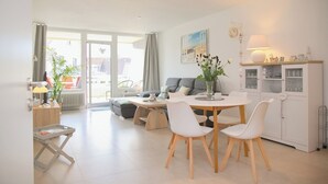 Un salon moderne comprenant un coin repas, un canapé, une table basse et un meuble avec des portes en verre.