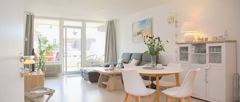 A modern living room with a dining area, a sofa, a coffee table, and a cabinet with glass doors.