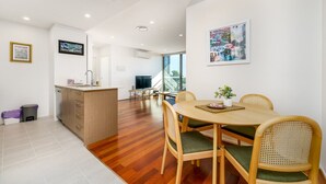 Une cuisine moderne avec des meubles en bois, un coin repas comprenant une table ronde et des chaises, et une grande fenêtre offrant une vue sur l’extérieur.