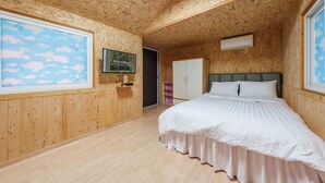 Un dormitorio con paneles de madera, una cama, un televisor y una puerta que da a otra habitación.