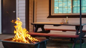 A fire pit with flames, a picnic table, and a window with a view of the sky. - Gapeong Restay Pension (Gapyeong)