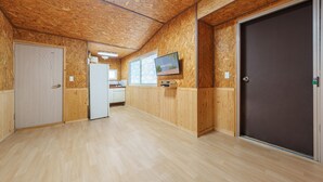 Un pasillo con paneles de madera, un refrigerador, un televisor y una puerta.