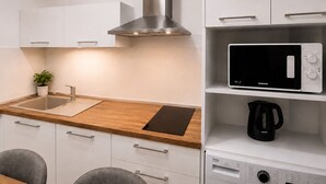 A modern kitchen with a stainless steel range hood, a microwave, and a coffee maker on the countertop. - Metropole Apartments Romana Square (Bucharest)