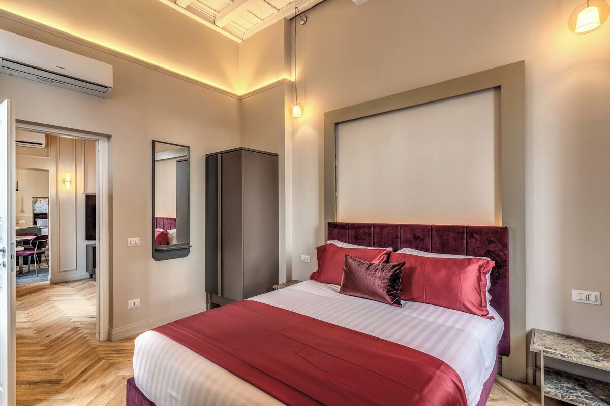 A hotel room with a large bed, a wardrobe, a desk, and a mirror.