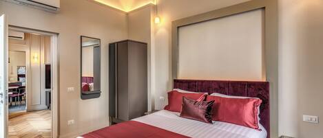 A hotel room with a large bed, a wardrobe, a desk, and a mirror.
