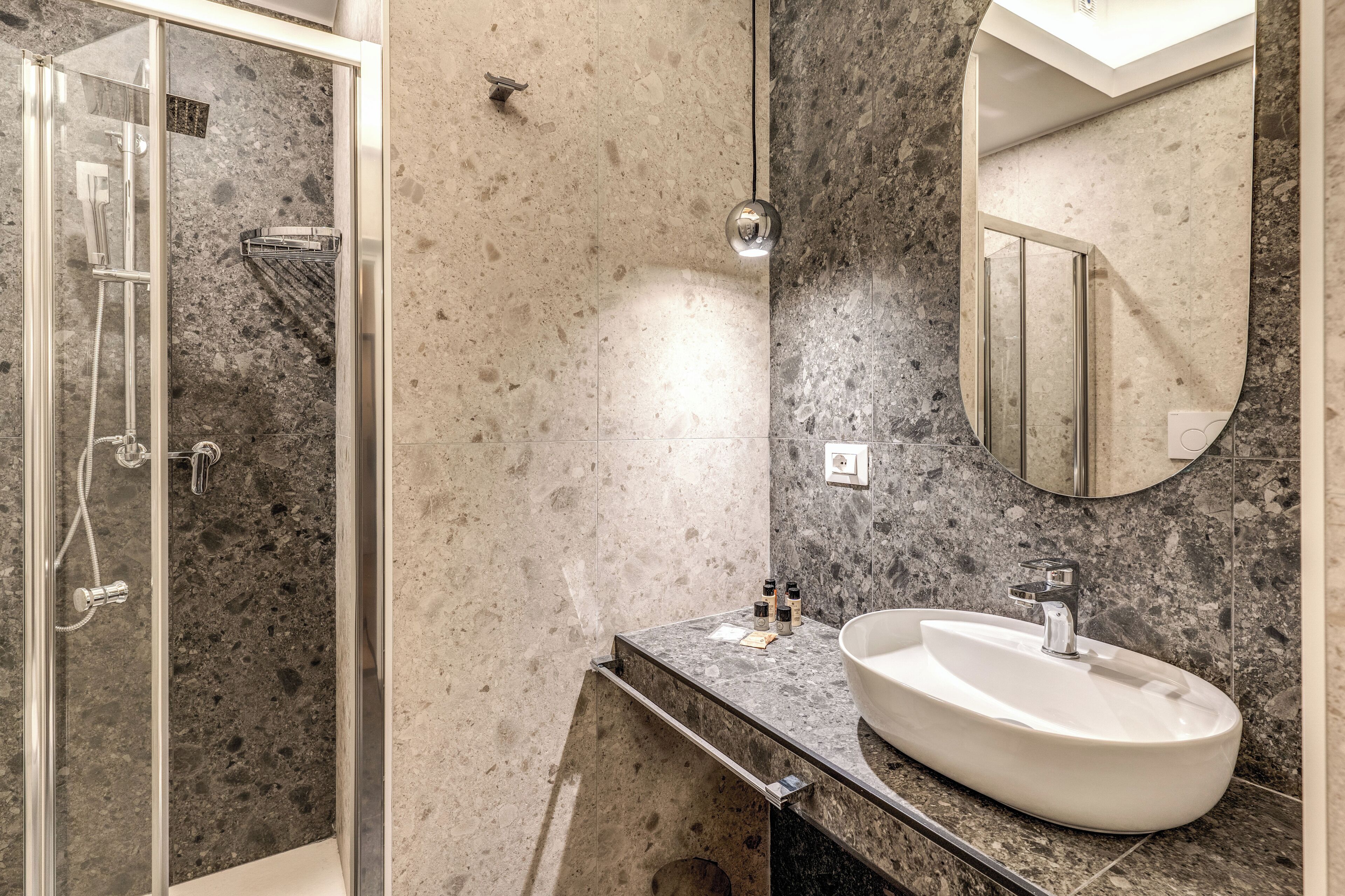 A modern bathroom with a glass-enclosed shower, a white sink, and a large mirror.