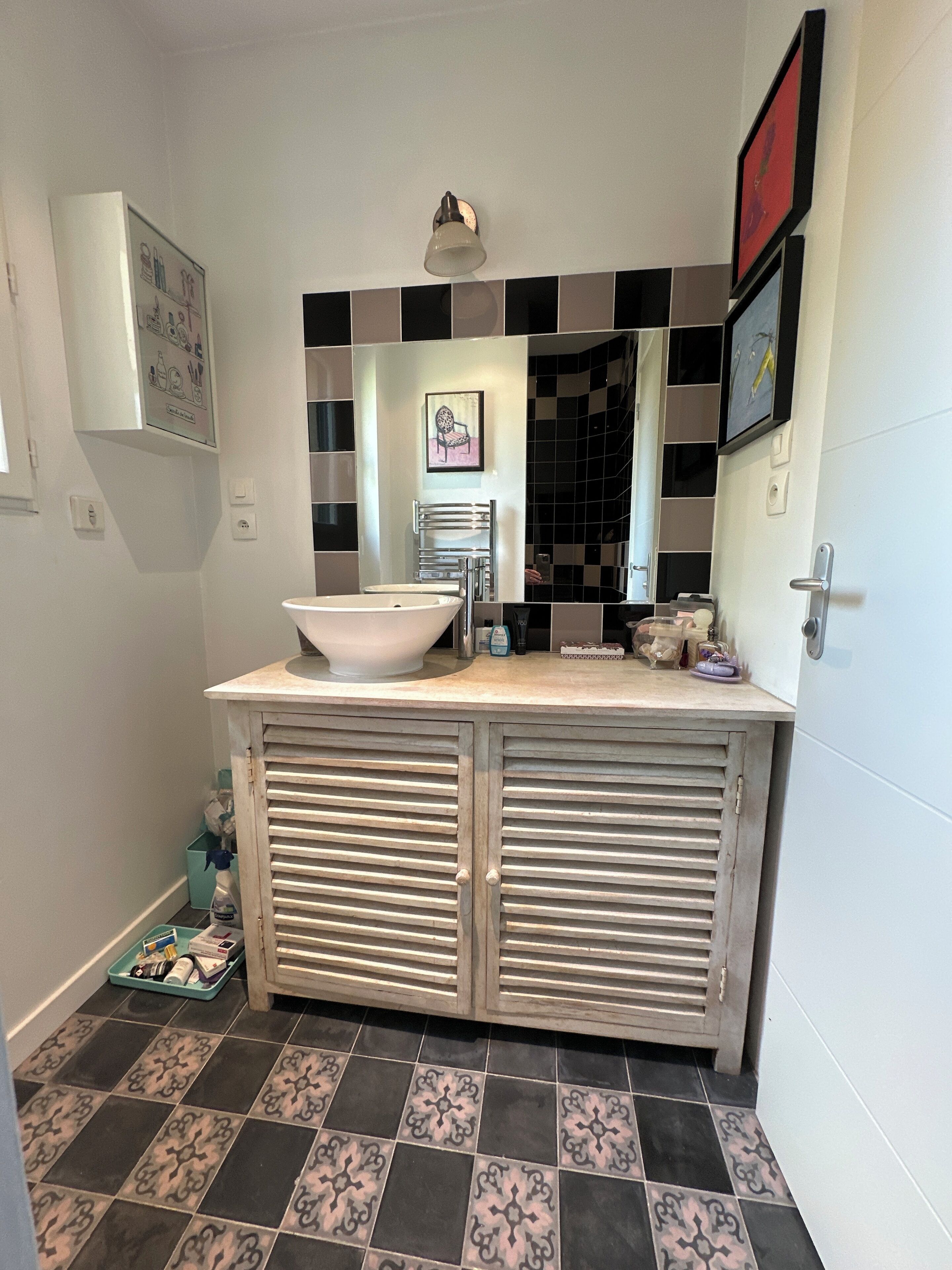 Une salle de bain avec un lavabo blanc, un pare-feu en carreaux noirs et blancs, et un porte-serviettes.