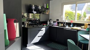 A modern kitchen with a central island, black cabinets, and a window providing natural light. - Room in contemporary house with swimming pool (Le Mans)