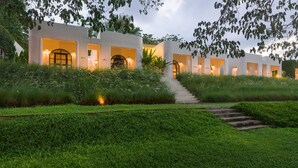 A modern building with multiple entryways, surrounded by lush greenery and a staircase leading to the entrance. - Villa La Flora Kaeng Krachan (Kaeng Krachan)