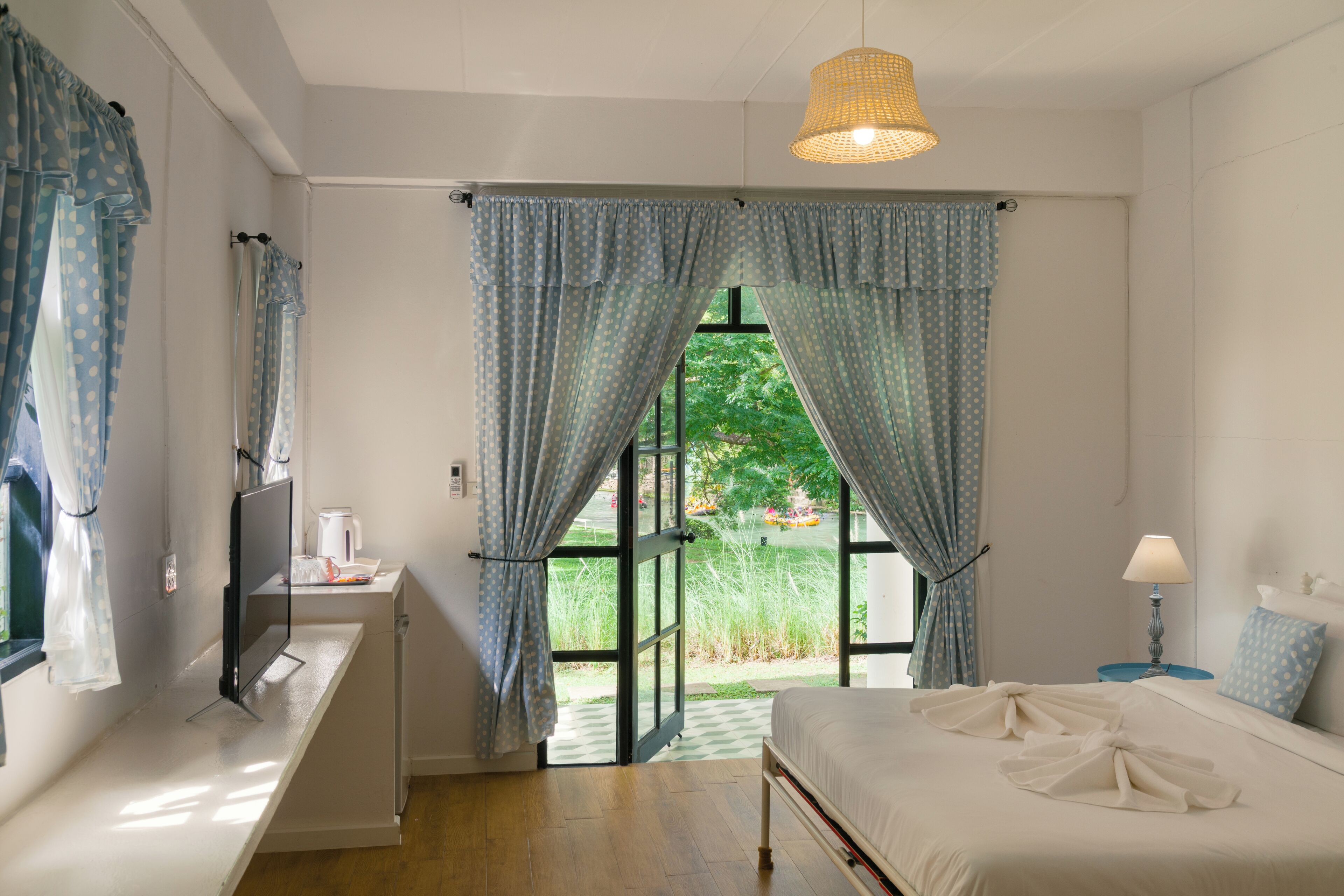 A bedroom with a bed, a desk with a computer, a lamp, and curtains.