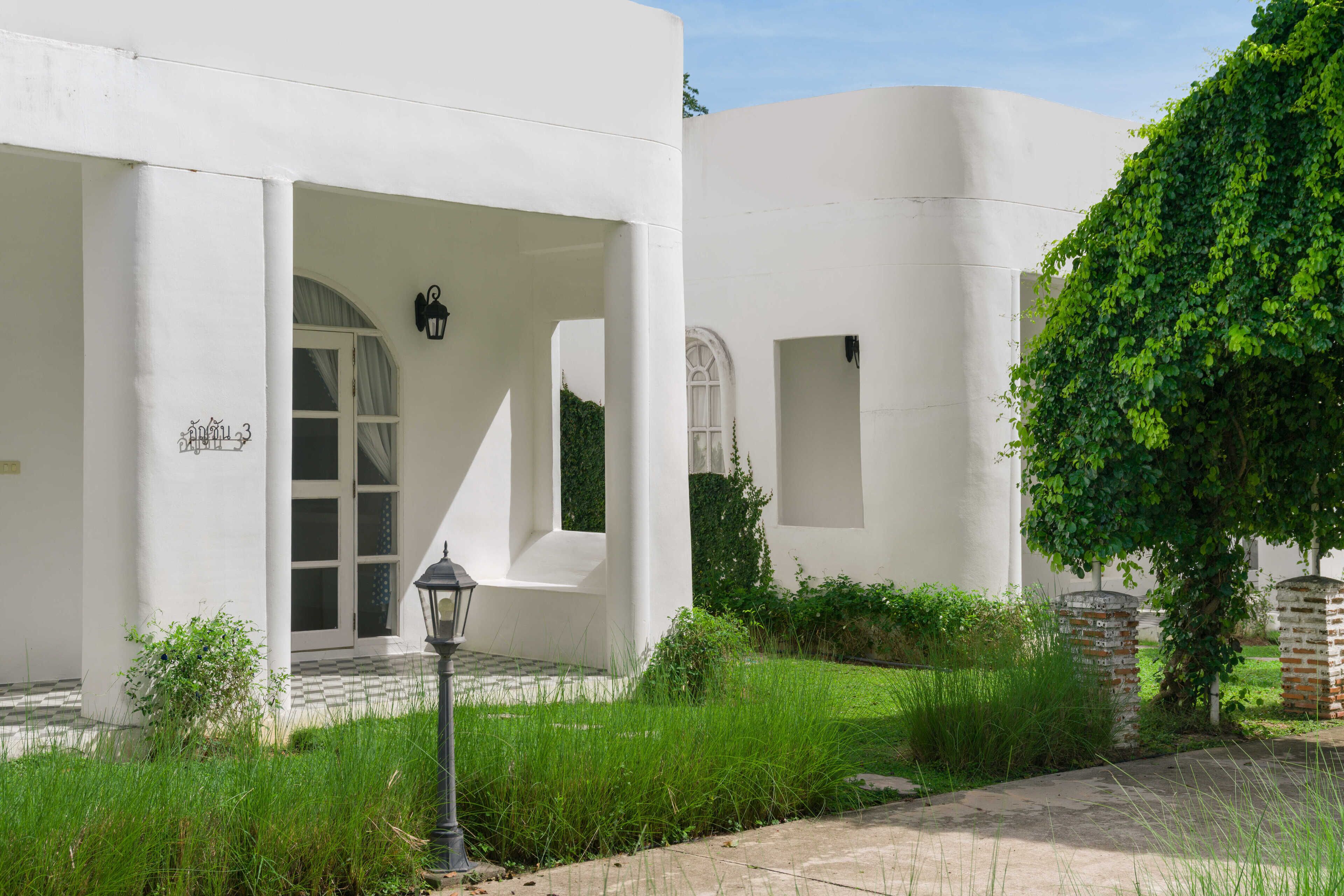 Un edificio blanco con ventanas arqueadas y una zona de entrada empedrada.