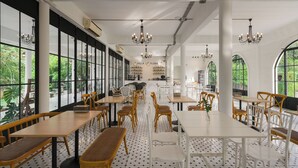 A spacious restaurant with high ceilings, large windows, and a variety of seating options including wooden tables and chairs. - Villa La Flora Kaeng Krachan (Kaeng Krachan)