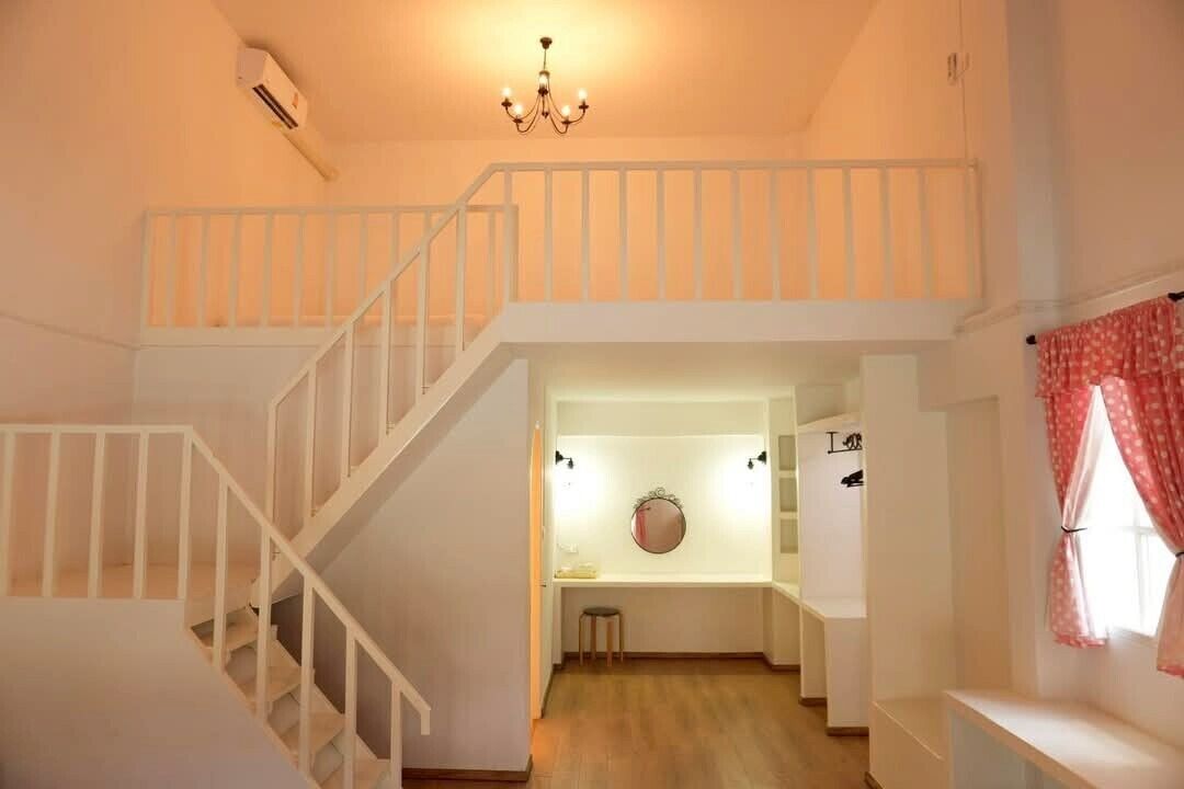Una escala condueix a un dormitori amb àtic, una làmpada de cristall i un petit tamboret.