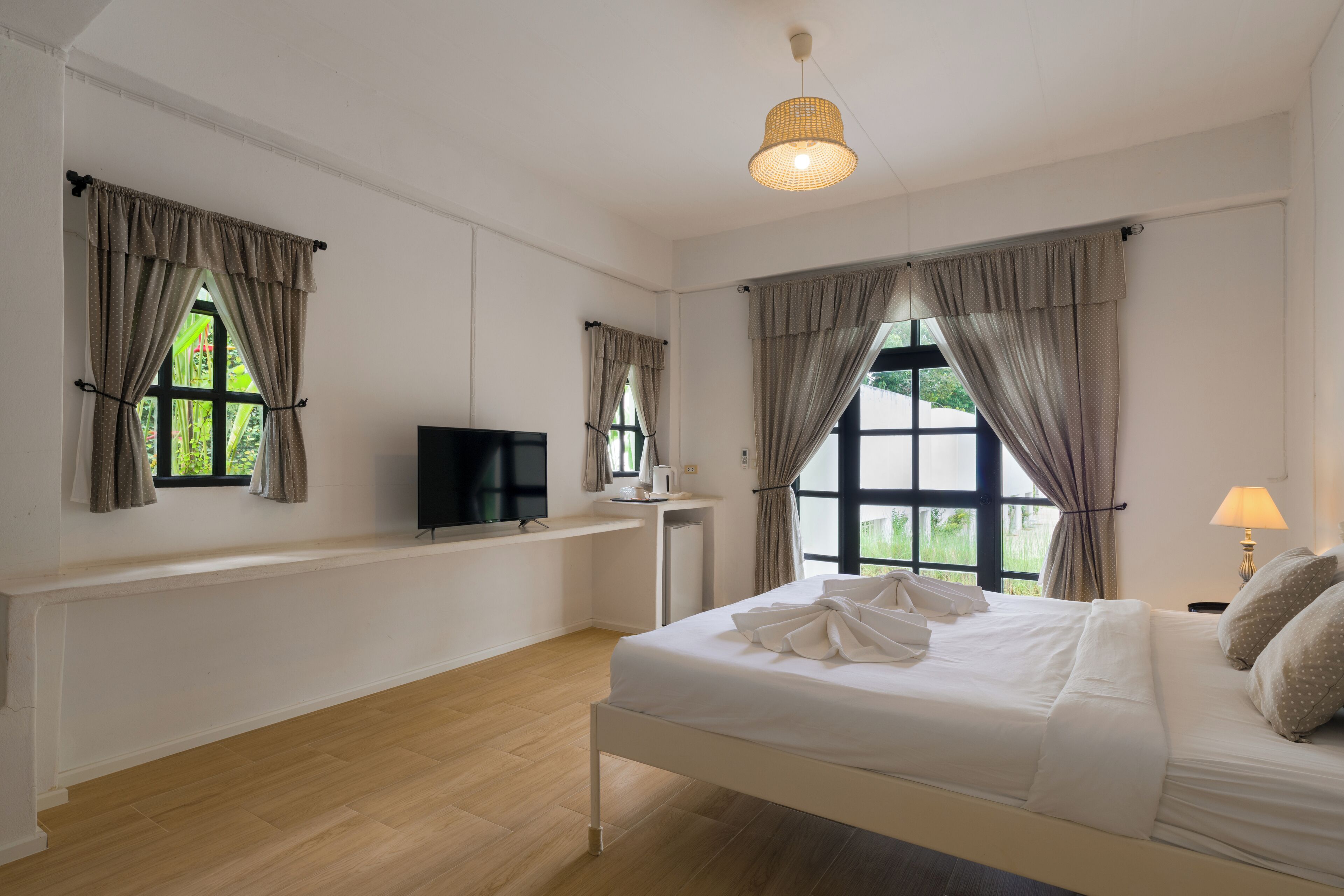 Une chambre d’hôtel avec un lit, une télévision, un bureau et une fenêtre avec des rideaux.