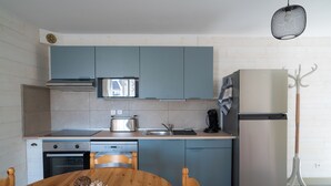 Una cucina moderna con armadietti blu, un frigorifero in acciaio inossidabile e un tavolo da pranzo in legno con una ciotola di cibo.