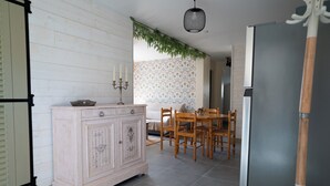 Una cucina con un armadietto in legno bianco, un tavolo da pranzo con sedie e un frigorifero.