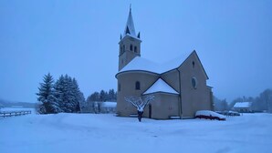 Una chiesa con un campanile slanciato e un tetto imbiancato dalla neve.