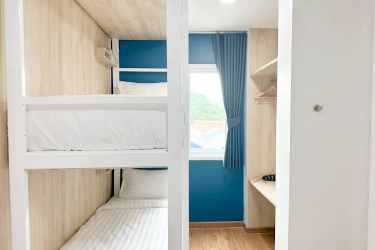 A bunk bed room with a window and curtains.