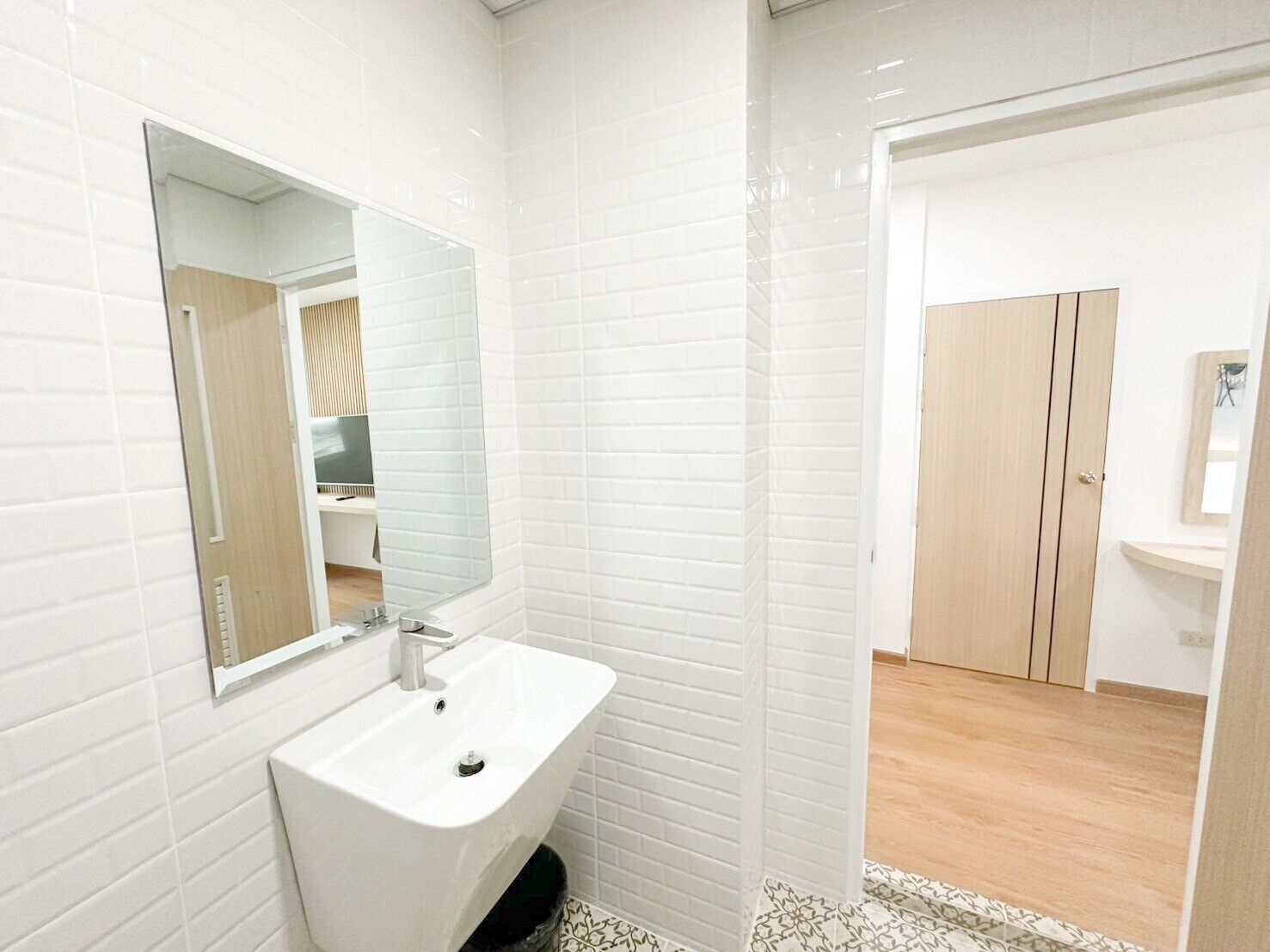 A modern bathroom with white subway tiles, a white sink, and a wooden vanity.