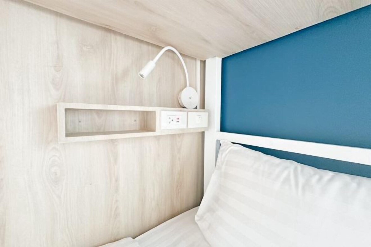Une chambre à coucher avec une tête de lit en bois, une table de chevet avec une lampe et une prise électrique.