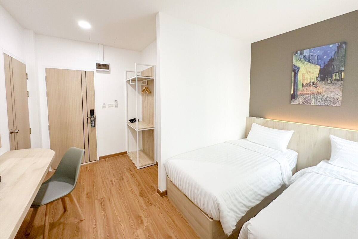Een hotelkamer met een bed, een bureau, een kledingkast en een schilderij aan de muur.