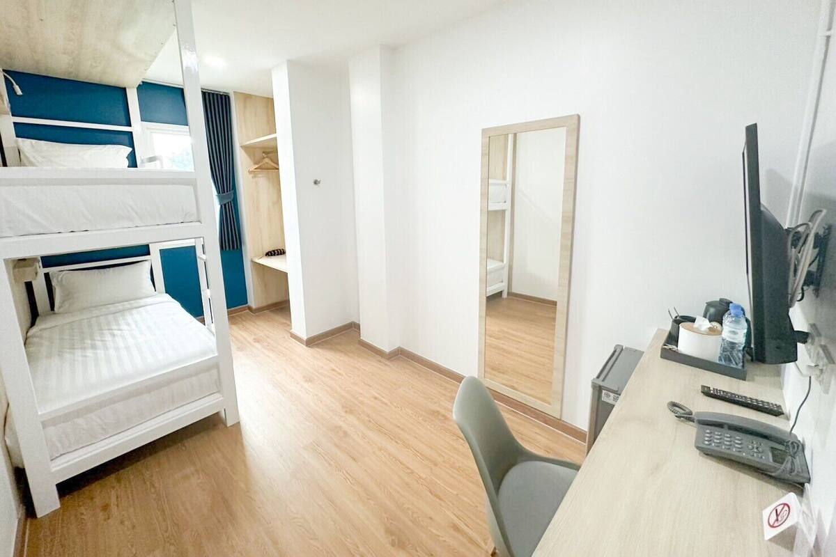 Een kamer met stapelbedden, een bureau met een computer, een spiegel en een stoel.