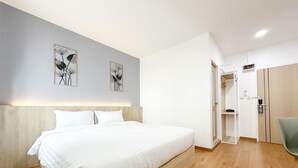 Quarto de hotel moderno com uma cama grande, piso de madeira e um guarda-roupa com espelho.
