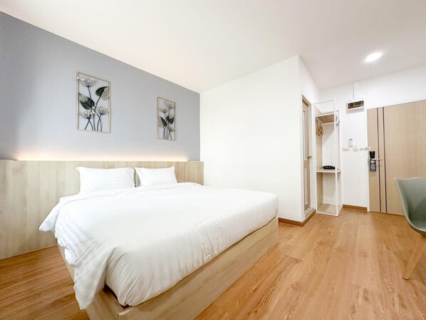 A modern hotel room with a large bed, wooden flooring, and a wardrobe with a mirror. - H-Banaat Hotel (Bangkok)
