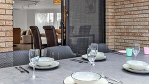 Un comedor con una mesa preparada para cuatro personas, incluyendo platos, vasos y cubiertos.