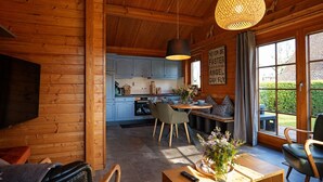 L’intérieur chaleureux d’un chalet comprend un coin repas, une cuisine et une grande fenêtre donnant sur le paysage extérieur.